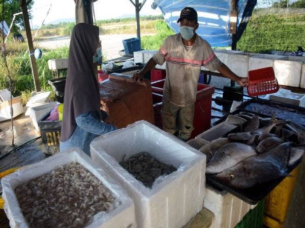 Seorang pekerja pasar mini, Abdul Halim Abdullah,33 (kanan) melayan pelanggan yang ingin membeli makanan laut yang dijual.- Foto Bernama