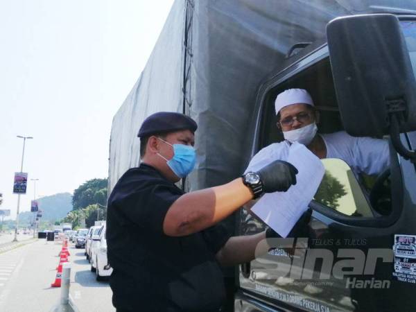 A Asmadi memeriksa surat kebenaran seorang pemandu lori ketika meninjau operasi sekatan jalan raya di Jalan Kuala Kangsar hari ini.
