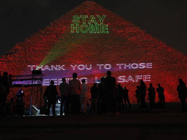 Orang berkumpul berhampiran Piramid Khufu diterangi dengan teks 'Kekal di rumah, terima kasih kepada mereka yang menjaga kami' di Giza, Mesir, semalam. Foto: Xinhua