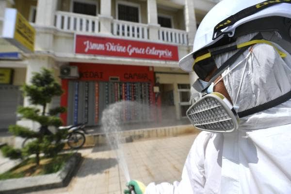 Kerja-kerja disinfeksi di sekitar bangunan kedai di Presint 15. -Foto Bernama