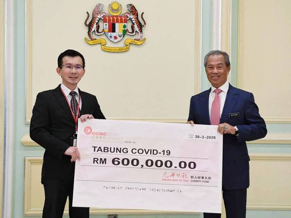 Perdana Menteri Tan Sri Muhyiddin Yassin menerima sumbangan daripada Pembantu Ketua Editor Kwong Wah Yit Poh Press Ng Yee Min pada Majlis Penyerahan Sumbangan Tabung COVID-19 dari sektor korporat di Bangunan Perdana Putra hari ini. - Foto Bernama