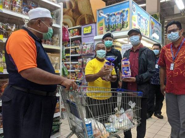 Mukhriz (dua, kanan) melihat barangan yang dibeli ketua keluarga ketika keluar rumah bagi mendapatkan bekalan di pasaraya.