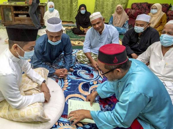 Pengantin lelaki Abdul Khalib Abdullah, 27, hanya melafazkan akad nikah tanpa bersalaman dengan Tok Iman Mukim Bukit Jeram Solahuddin Ali, 52, ketika melangsungkan pernikahannya bersama pengantin perempuan Nurul Fatihah Mat Husin, 27, di Kampung Bukit hari ini.-fotoBERNAMA