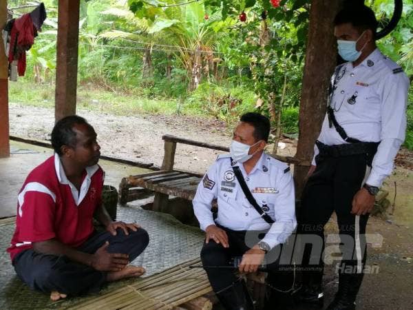 Sarjan Mohd Sanusi (tengah) dan Lans Koperal Muhammad Zairi Mohd Nawi dari IPD Hulu Terengganu sewaktu membuat pemantauan di perkampungan orang Asli di Sungai Berua.