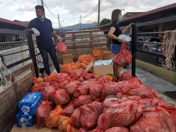 Arul Kumar (kiri) semasa mengagih sayur-sayuran di sekitar Mantin.