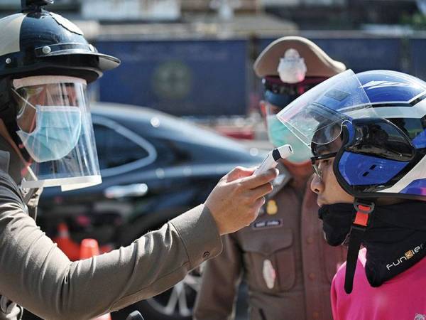 Polis Thailand menjalankan pemeriksaan suhu ke atas pengguna jalan raya di pinggir Bangkok.