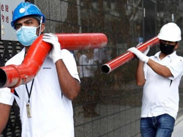 Pekerja asing di Singapura memakai topeng muka sebagai langkah berjaga-jaga wabak Covid-19 yang kini melanda penempatan asrama mereka di Singapura. - Foto Agensi