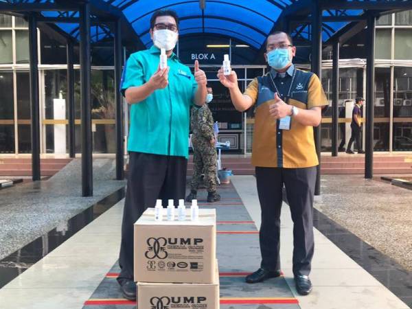 Saharudin menyerahkan sumbangan pensanitasi tangan kepada Md Yusli untuk diagihkan kepada petugas barisan hadapan.