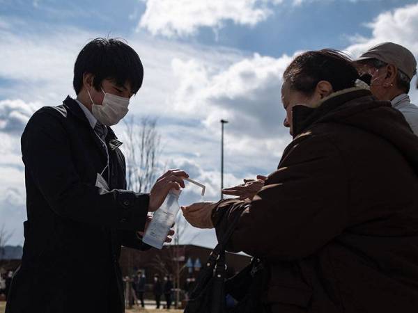 Orang ramai diberikan pensanitasi tangan sebagai langkah mencegah penularan Covid-19 di Jepun.