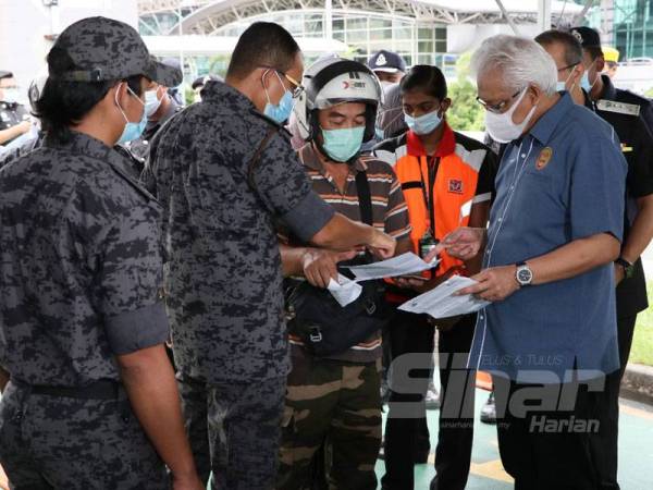 Hamzah (kanan) melakukan pemeriksaan terhadap seorang penunggang motosikal semasa melakukan lawatan di Kompleks Kastam, Imigresen dan Kuarantin (CIQ) Bangunan Sultan Iskandar (BSI), Johor Bahru hari ini.