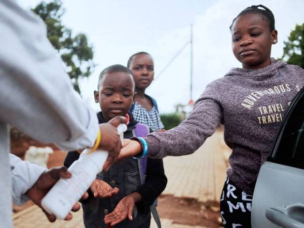Anggota Persatuan Palang Merah Antarabangsa (IRC) menyediakan pensanitasi tangan kepada orang ramai di Soweto, Afrika Selatan.