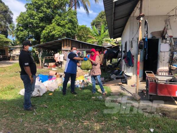 Nik Abdul Aziz (dua, kanan) menyampaikan bantuan makanan berbentuk beras, biskut dan gula kepada keluarga Amelia. 