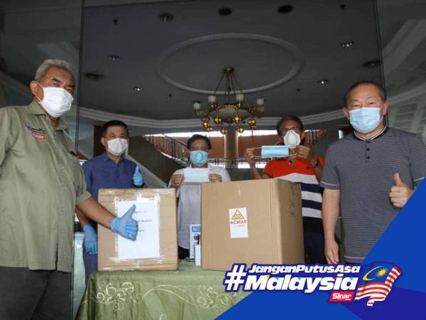 Steven (kanan) menyerahkan kotak berisi penutup hidung dan mulut kepada Hashim. - FOTO ASRIL ASWANDI SYUKOR