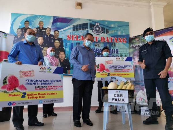 Aminuddin (tengah) menyerahkan bakul buah-buahan kepada Mohamad (kanan). Turut kelihatan Basri (kiri).