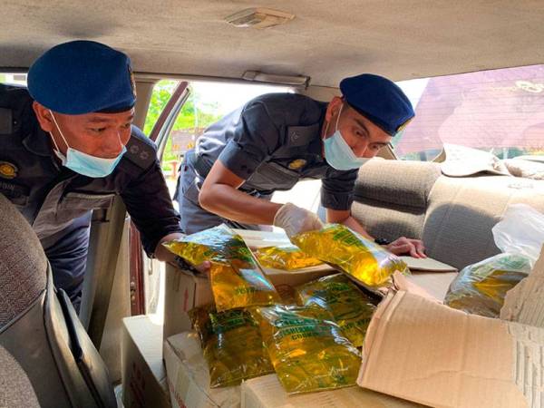 Azizi (kanan) menunjukkan minyak yang dijumpai dalam kenderaan tersebut.