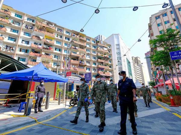 Anggota polis dan tentera berkawal di sekitar Flat Selangor Mansion dan Malayan Mansion selepas kerajaan melaksanakan Perintah Kawalan Pergerakan Diperketatkan (PKPD) di dua bangunan tersebut berikutan penemuan 15 kes COVID-19 ketika tinjauan di Jalan Masjid India hari ini. - Foto Bernama