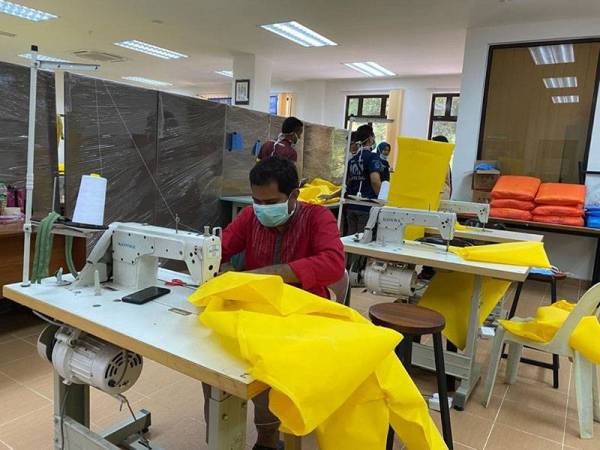 Seorang pensyarah yang turut menjadi sukarelawan Briged Menjahit Covid-19 UIAM menjahit set PPE untuk digunakan petugas barisan hadapan.