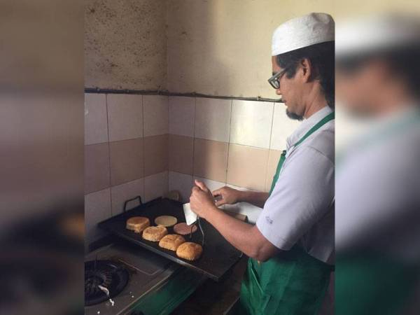 Bapa Muhammad Faisal, Mohamad Roslan Mohamed Sokur, 52, menyediakan tempahan burger pelanggannya di rumah.