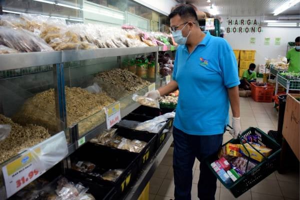 Seorang pelanggan memilih barang keperluan harian termasuk ikan bilis di sebuah pasar raya. -Foto Bernama