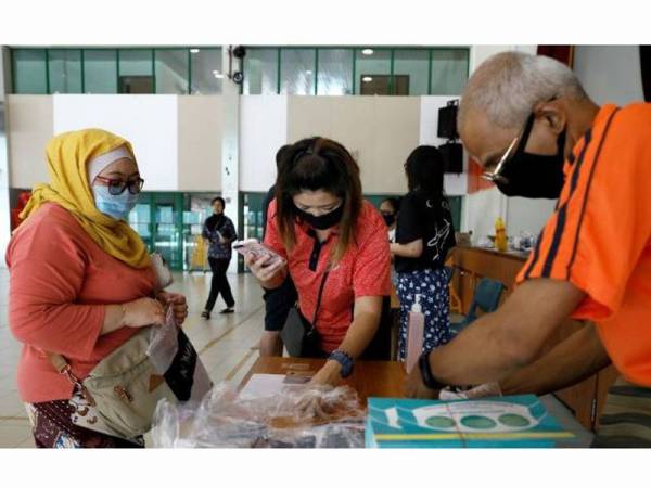 Penduduk Singapura menerima topeng muka percuma di pusat komuniti. -Foto Al Jazeera
