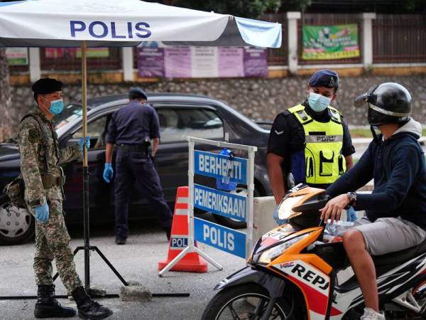 Anggota polis dan Angkatan Tentera Malaysia (ATM) memeriksa dan menyoal orang awam yang melalui sebuah sekatan jalan raya sekitar ibu kota. - Foto Bernama