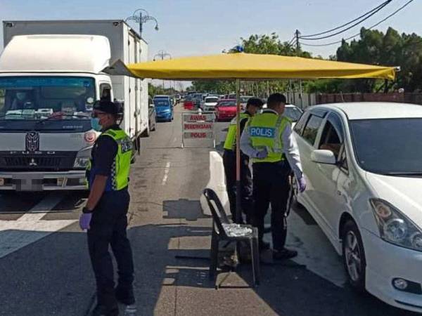 Anggota polis dan trafik memantau sekatan jalan raya menghala pusat bandar ketika tempoh PKP dikuatkuasakan.