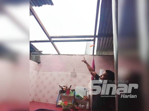 Mohd Zairi menunjukkan bumbung di bahagian dapur rumahnya yang diterbangkan angin dalam kejadian ribut petang semalam.