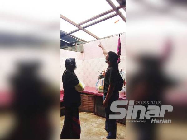 Noor Ashikin dan suaminya Mohd Zairi menunjukkan bumbung di bahagian dapur rumah mereka yang diterbangkan angin dalam kejadian ribut petang semalam.