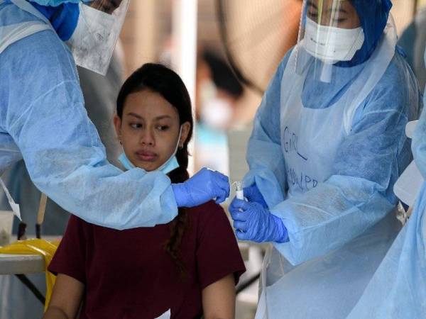 Seorang penduduk melihat sampel yang diambil petugas KKM selepas membuat saringan Covid-19 di Sekolah Rendah Agama Jalan Raja Muda Musa semalam.