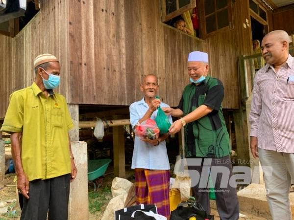 Mohd Adanan (dua dari kanan) menyampaikan bekalan makanan kepada Ismail Ab Rahman.