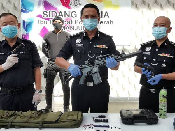 Nor Omar (tengah) menunjukkan raifal tirua. yang dirampas daripada suspek bersama dua pistol tiruan.