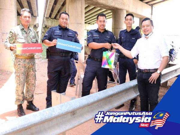 Ken (kanan) ketika mengagihkan sumbangan kepada anggota polis dan tentera yang bertugas di lapangan. 