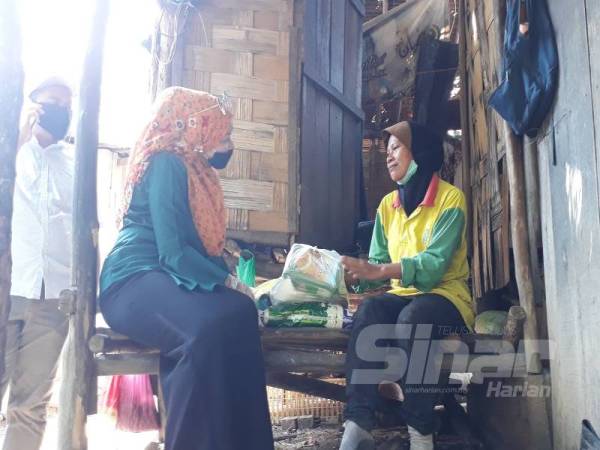 Rukiza (kiri) menyampaikan sumbangan barangan keperluan bagi meringankan beban Syarifah sepanjang tempoh Perintah Kawalan Pergerakan (PKP) yang sedang berlangsung sehingga 28 April. 