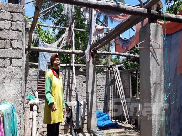 Syarifah berada di ruang tengah rumah yang dibinanya sejak 2018 namun masih belum siap. Kayu-kayu yang digunakan untuk membuat bumbung diambil dari bukit di tepi kampungnya. 