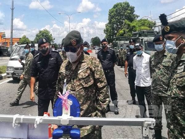 Ahmad Hasbullah (tengah) melihat papan tanda di sekatan jalan raya Kampung Gong Pauh dalam lawatannya di sini hari ini. 