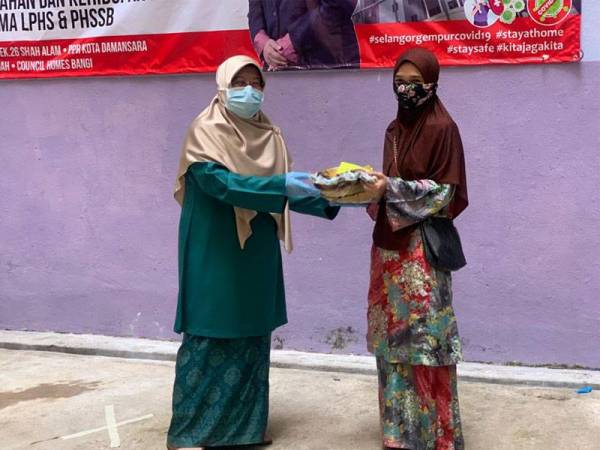 Haniza (kiri) menyampaikan sumbangan bantuan makanan keperluan kepada seorang penyewa di PPR Kampung Baru Hicom pagi tadi