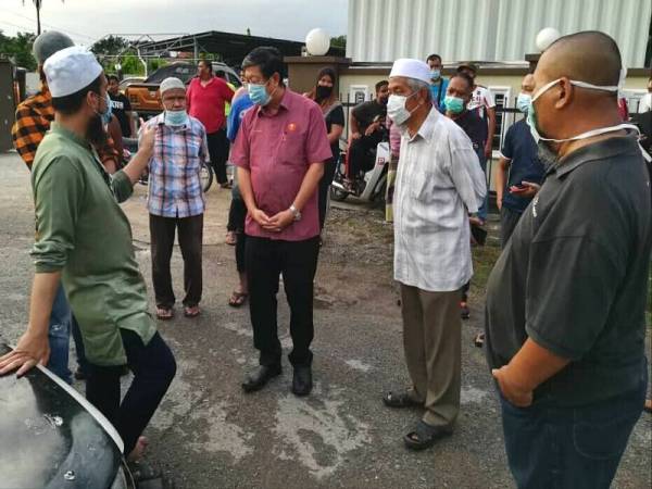 Kok Yew (tiga dari kanan) dan Ustaz Ebit (kiri) ketika berada di rumah usang dihuni Ishak sekeluarga di Lorong Gedebang sebelum keluarga itu dipindahkan semalam.