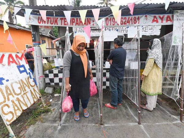 Pemilik premis menjual ayam mengambil inisiatif dengan membuat penghadang diperbuat daripada plastik bagi memastikan pembeli dapat mengekalkan penjarakan sosial sebagai langkah mengekang penularan COVID-19 ketika tinjauan di Bukit Tok Beng hari ini. - Foto Bernama