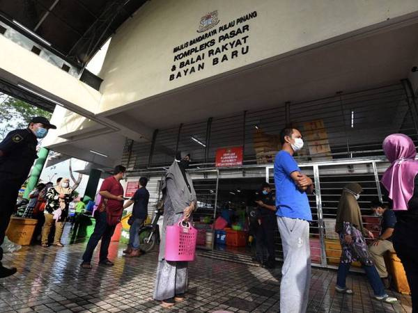 Umat Islam beratur panjang untuk membeli barang basah sebagai persiapan menyambut Ramadan esok, dengan mengamalkan penjarakan sosial dan memakai penutup hidung dan mulut di Kompleks Pasar dan Balai Rakyat Bayan Baru hari ini. - Foto Bernama