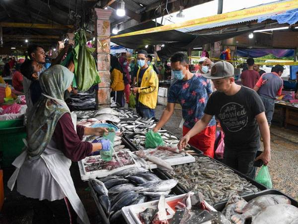Orang ramai membeli barangan basah seperti ikan, sotong dan udang sebagai persediaan bagi menyambut Ramadan dalam tempoh Perintah Kawalan Pergerakan (PKP) ketika di Pasar Borong Gong Pauh hari ini. - Foto Bernama