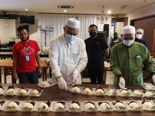 Razman membantu penyediaan makanan yang akan diedar kepada petugas barisan hadapan yang disediakan Ipoh Central Kitchen (ICK) di Restoran Simpang Tiga hari ini.