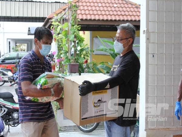 Mustaffa Hassan, 58, (kiri) menerima sumbangan pek makanan asas daripada wakil pihak Islamic Aid Malaysia, rakan kemanusiaan Maybank Islamic di PPR Kerinchi, Kuala Lumpur.