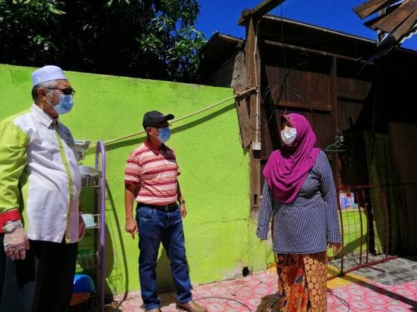 Rokayah menunjukkan keadaan bumbung dapur rumahnya yang hilang dalam kejadian ribut, kelmarin.