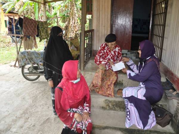 Ketua Pergerakan Wanita UMNO Bahagian Besut Engku Naemah Engku Taib (kanan) menyampaikan sumbangan kepada warga emas Hasnah Awang, 70, (dua, kanan) di Cegar Batang, Pasir Akar, Hulu Besut hari ini. - Foto Bernama 
