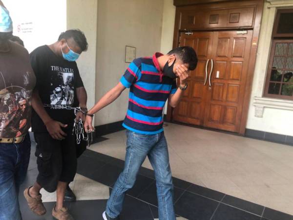 Mohamad Khidzir (kanan) dibawa keluar dari Mahkamah Majistret Kuala Lumpur hari ini selepas mengaku bersalah menyamar anggota tentera dan ingkar PKP.