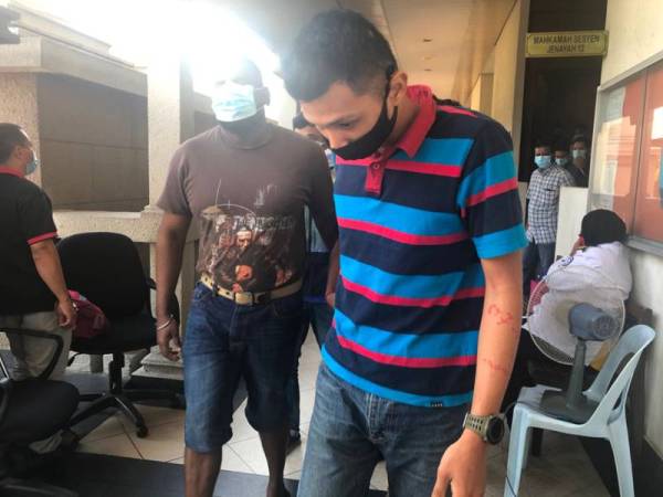 Mohamad Khidzir (kanan) dibawa keluar dari Mahkamah Majistret Kuala Lumpur hari ini selepas mengaku bersalah menyamar anggota tentera dan ingkar PKP.