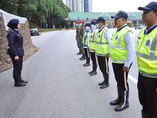 Juliana (kiri) memberi taklimat kepada anggota yang bertugas di sekatan jalan raya Plaza Tol Jalan Duta, Kuala Lumpur.