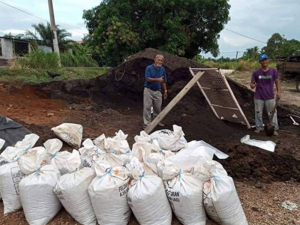Janian (kiri) bersama menantunya ketika membuat tanah semaian.