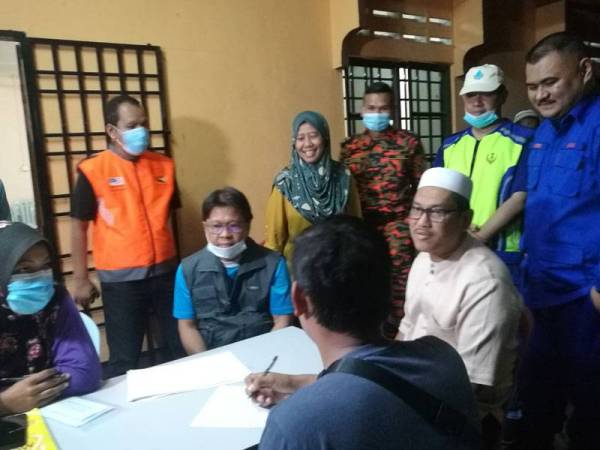 Ahmad Faizal (duduk, dua dari kanan) ketika melawat mangsa ribut di Dewan Orang Ramai Kampung Seri Klebang di sini yang turut disertai Asmuni.