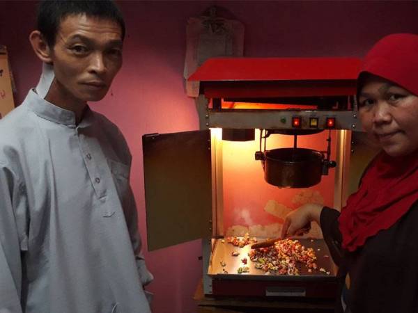 Muhammad Adam Lai (kiri) dan isterinya menunjukkan mesin membuat bertih jagung yang dibeli hasil pinjaman modal diberikan kepada mereka.